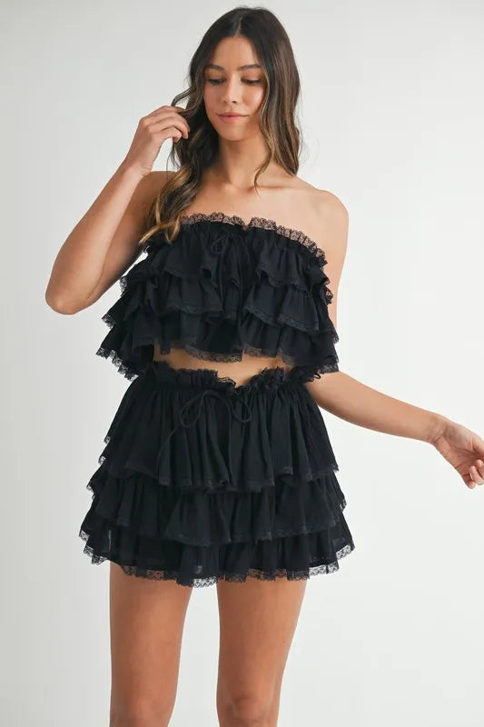 Model wearing a layered ruffle black crop top with matching mini skirt set
